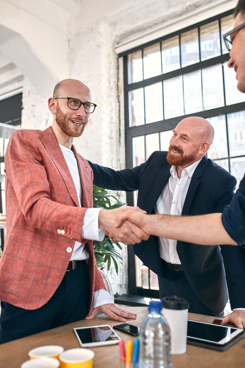 Business handshake at meeting or negotiation in the office. Partners are satisfied because signing contract or financial papers. selective focus.